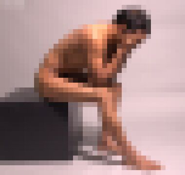 A profile of a nude desi man with short black hair sitting on the edge of a black box, leaning forward with his head in his hands