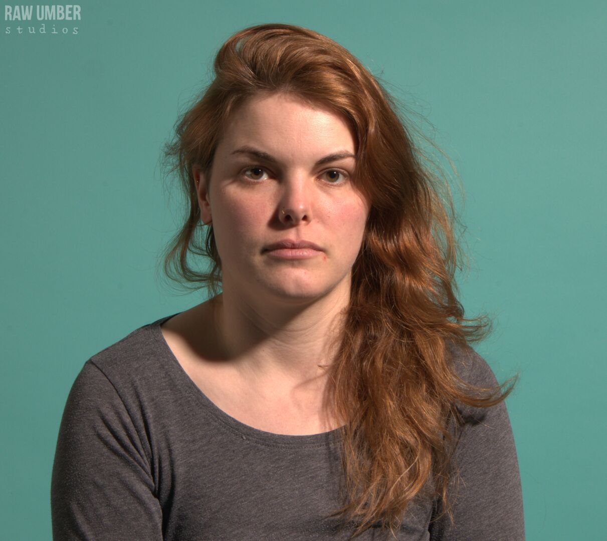 A white woman with medium-length asymmetric brown hair looking straight at the camera with a neutral expression