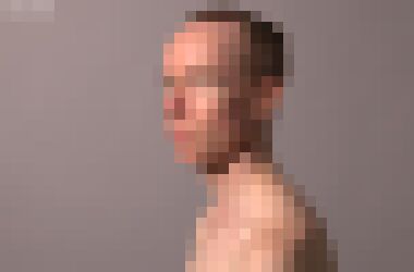 A white male with a receding hairline and hair tied at the back in a three quarter profile staring at the camera