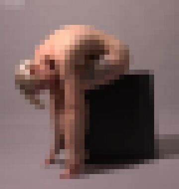 A nude white woman with short platinum blonde hair sitting on a black box and bending at the waist until her hands grasp her ankles, bowing her head and glancing at the camera with a neutral expression
